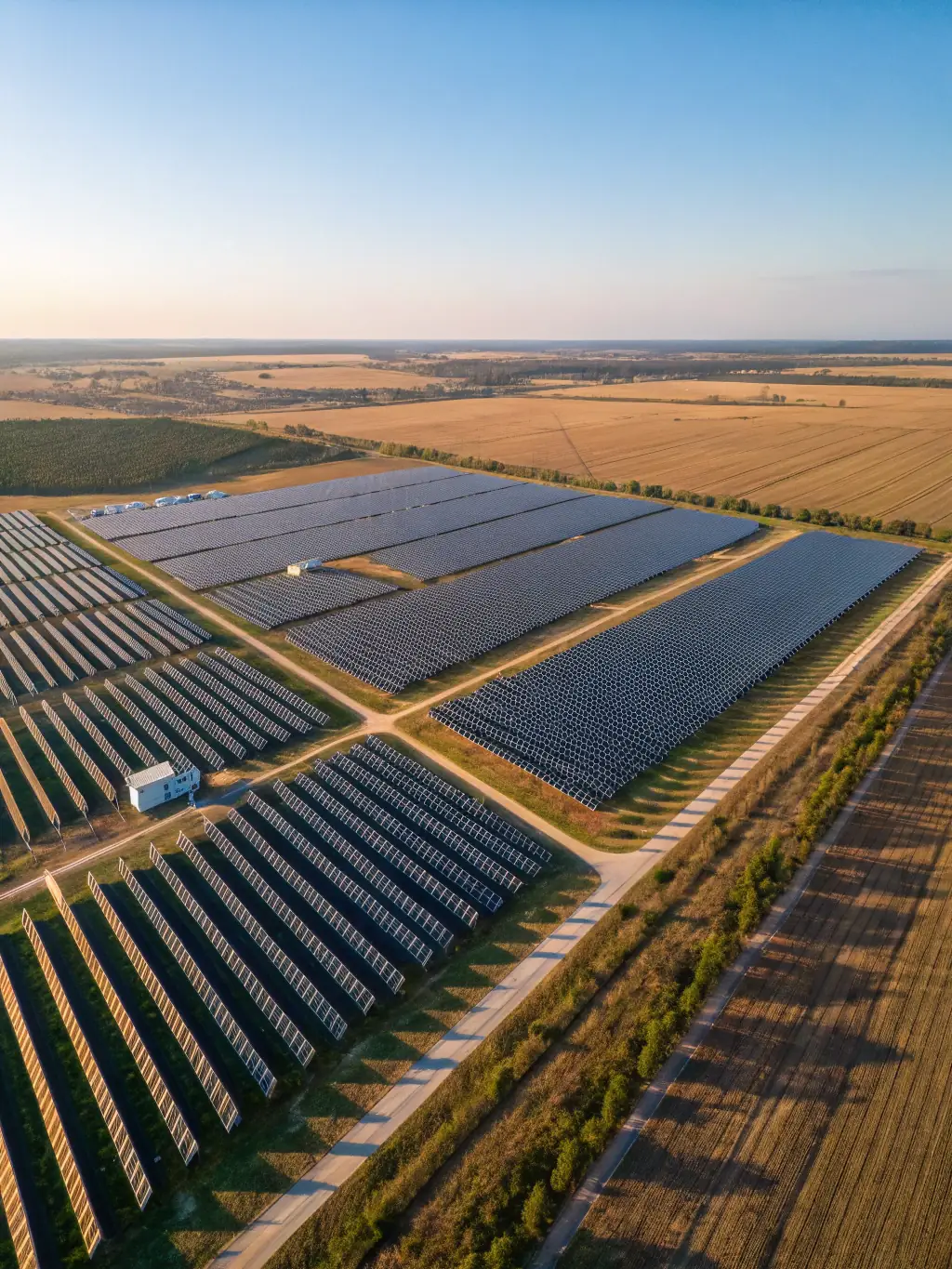 A wide shot of a ground-mounted solar panel array installed on school grounds, showcasing the scale and efficiency of the system.