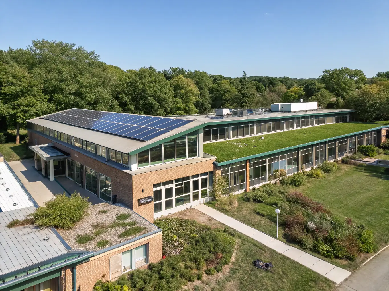 An aerial shot of a school building with solar panels installed on the roof, set against a clear blue sky. The image highlights the visual impact and integration of solar energy into the school's infrastructure.